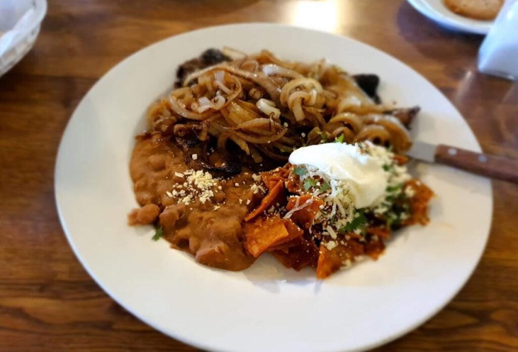 A plate of chilaquiles with refried beans and scrambled eggs, served at El Meson de Mustafa in the Valle de Guadalupe. Valle de Guadalupe Mexico Tour.