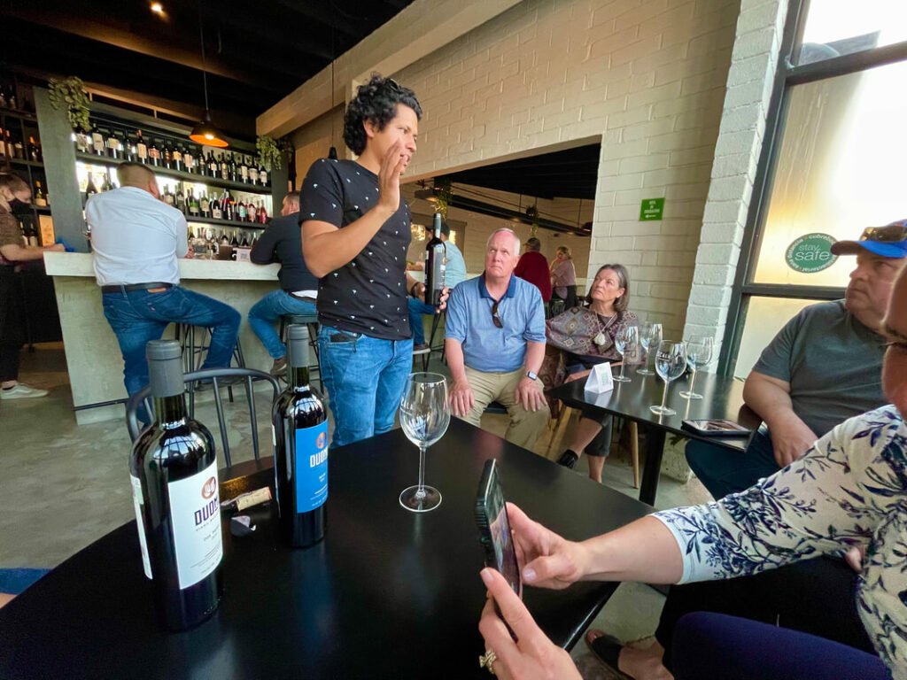 A casual social gathering in a bar, with people enjoying drinks and conversations amid a lively atmosphere during their Mexico wine tours.