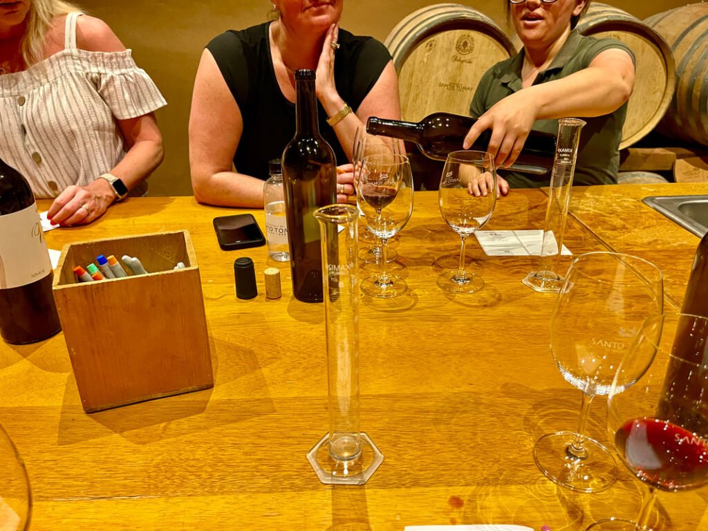 Wine tasting with three people at a wooden table.